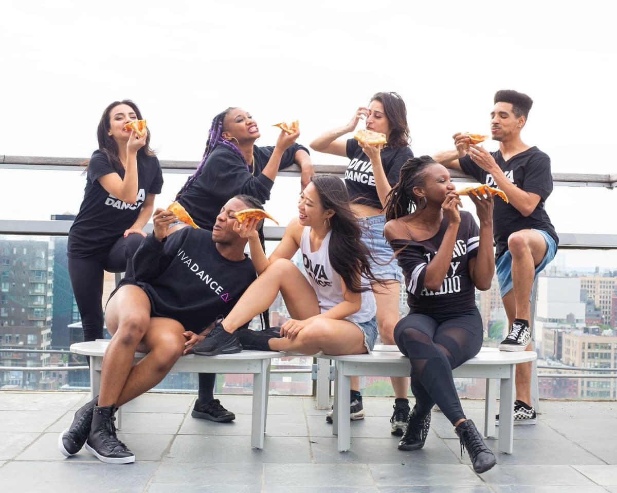 Dancers eating pizza together on a rooftop